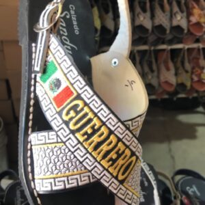 Close-up of a Guerrero sandal with a patterned strap and gold lettering in a shoe store.